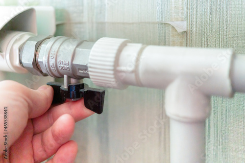 Man opens the valve of a metal radiator central heating in the room