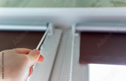 man opens / closes the roller blinds installed on the window