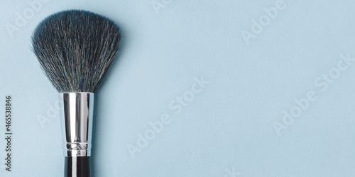 Large makeup brush on a blue background.