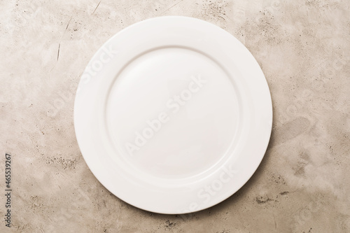 Empty white ceramic plate on light abstract background, top view, food background