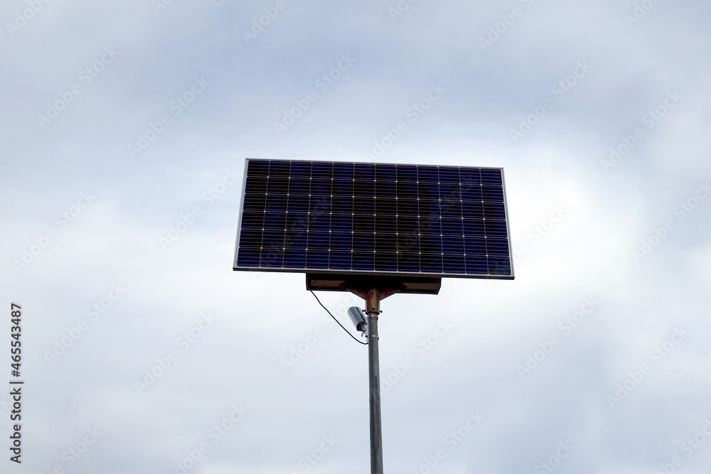 Obraz premium Solar panels on a pillar against the backdrop of a cloudy sky. Green energy concept