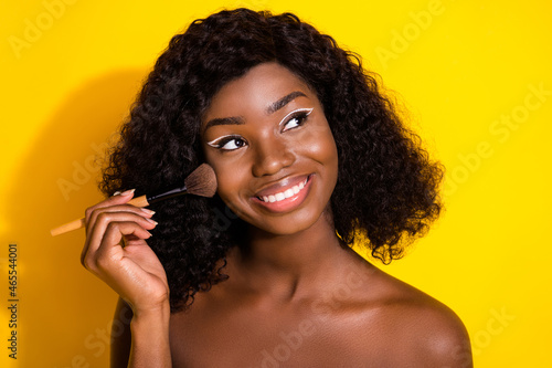 Photo of young happy smiling lovely dreamy african girl look copyspace apply highlighter isolated on yellow color background