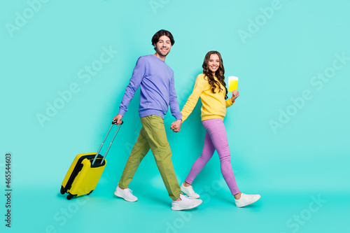 Full size profile side photo of young couple happy smile go walk registration flight tickets bag isolated over teal color background