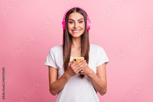 Portrait of attractive cheerful girl using device gadget chatting listening hit isolated over pink pastel color background