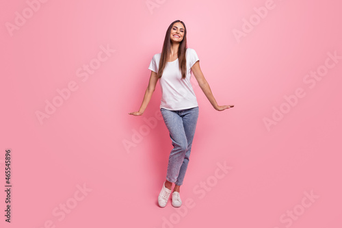 Full size photo of funny young brunette lady dance wear t-shirt jeans sneakers isolated on pink background