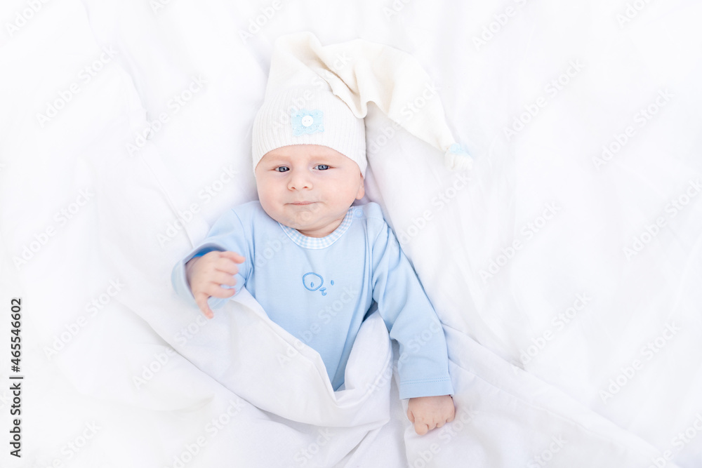 baby boy on the bed under the blanket in the hood, healthy sleep of the newborn baby boy on the bed under the blanket in the hood, healthy sleep of the newborn