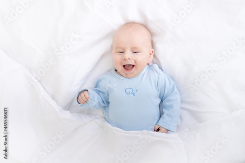 laughing baby boy on the bed under the blanket, healthy sleep baby