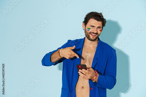 Young man wearing blue jacket pointing finger at his cellphone