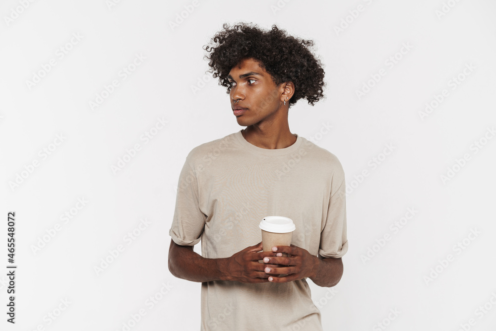 Young black man in t-shirt looking aside while drinking coffee Young black man in t-shirt looking aside while drinking coffee