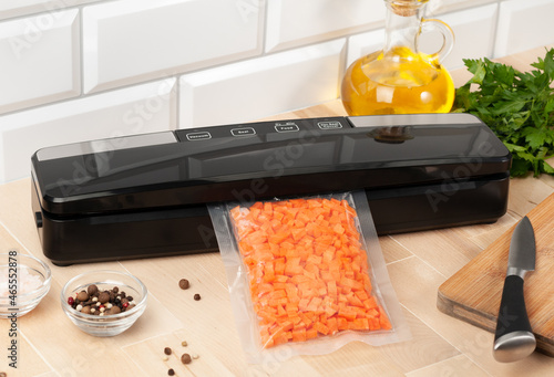 Vacuum packing machine. For long-term storage of food. Packs chopped carrots. Top view light background. photo