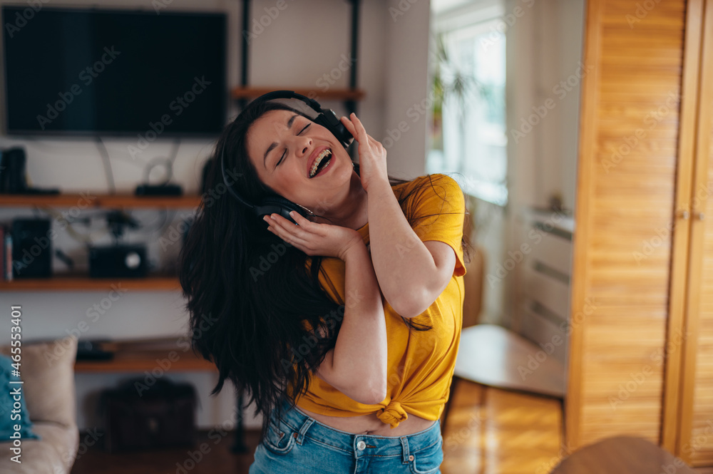 Young beautiful woman dancing at home while listening music