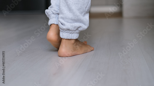 Close up of barefoot young female walking on warm heated wooden floor at home. step in her bare feet relaxing enjoy free sunny day.