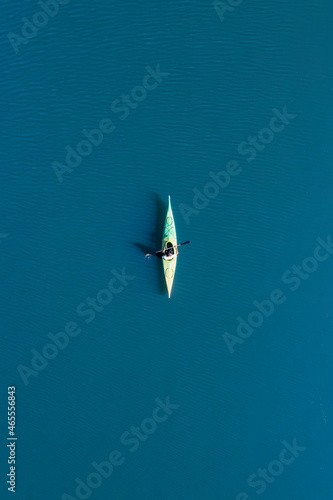 Obraz na płótnie View from above, aerial view of a person paddling a canoe - kayak on the Cedrino Lake surrounded by the mountain range of Supramonte located northeast of the Gennargentu massif. Sardinia, Italy. w salonie
