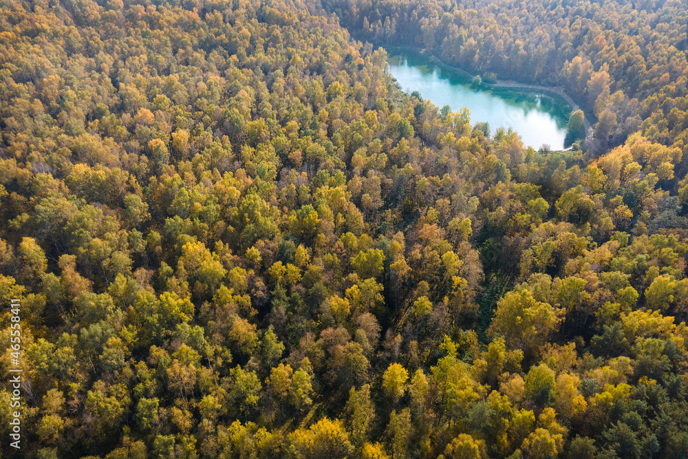 Little  lake of turquoise shade in the middle of a multi colored autumn forest, aerial photography. An ideal quiet place for a family holiday.