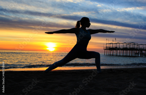 Silhouette of a girl doing yoga at sunset by the sea