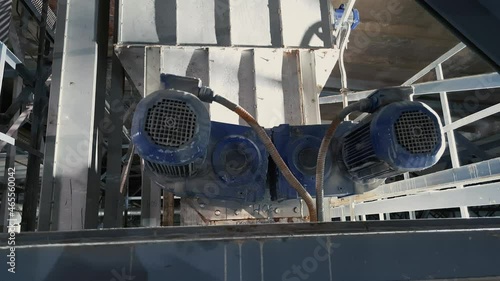 Two blue induction motors are in operation in a industrial plant. One of them is loose, poorly fixed.