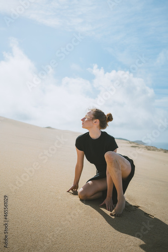 Woman squatting on sandy dune in arid valley