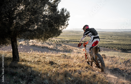 Unrecognizable man riding motorcycle in forest photo