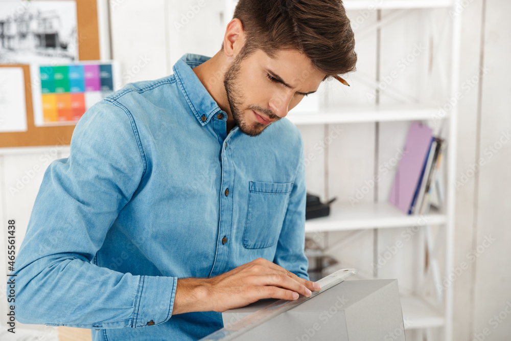 Young white man working with material sample in office
