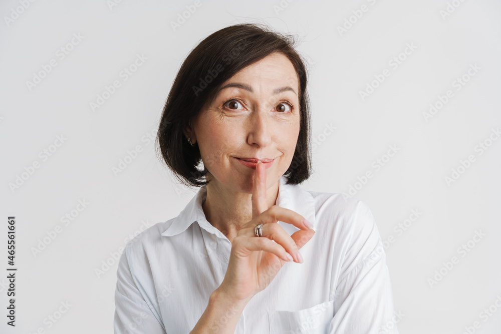 European mature woman smiling and showing silence gesture European mature woman smiling and showing silence gesture