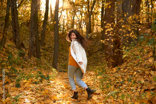 cheerful and happy girl runs away in yellow autumn forest. blurred photo