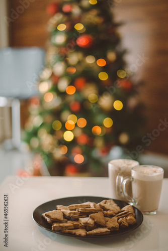 Christmas background with homemade gingerbread and two cups of hot cocoa  christmas lights on the Christmas tree  bokeh