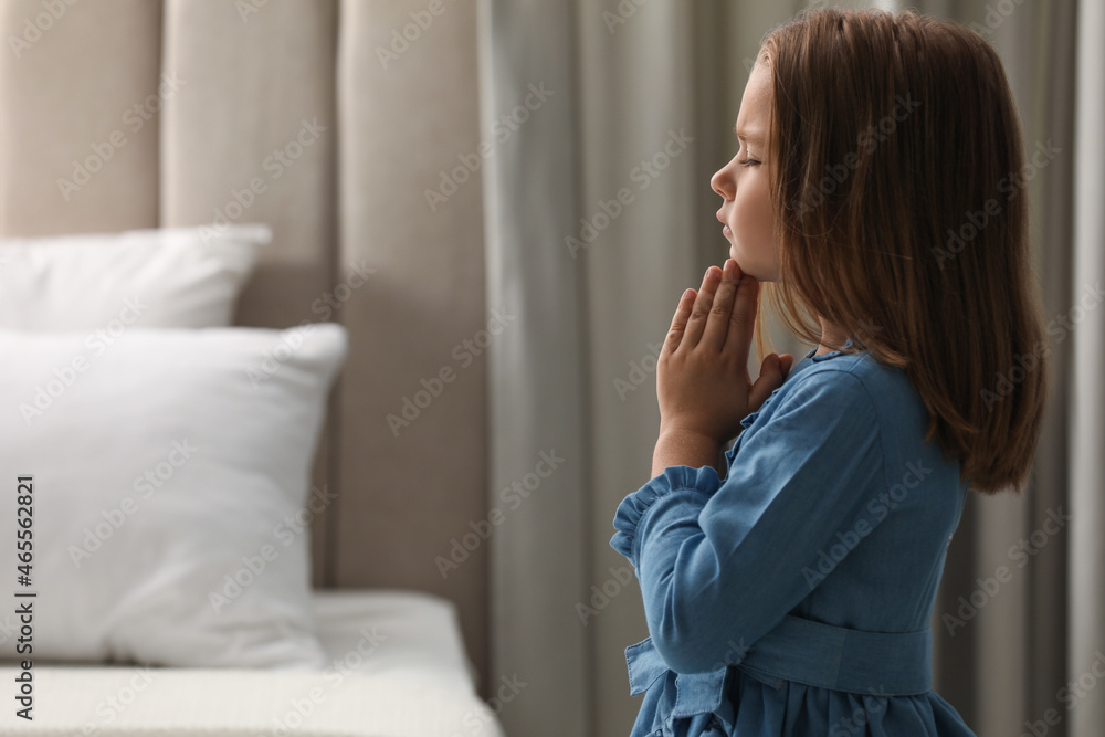 Cute little girl saying bedtime prayer at home. Space for text Cute little girl saying bedtime prayer at home. Space for text