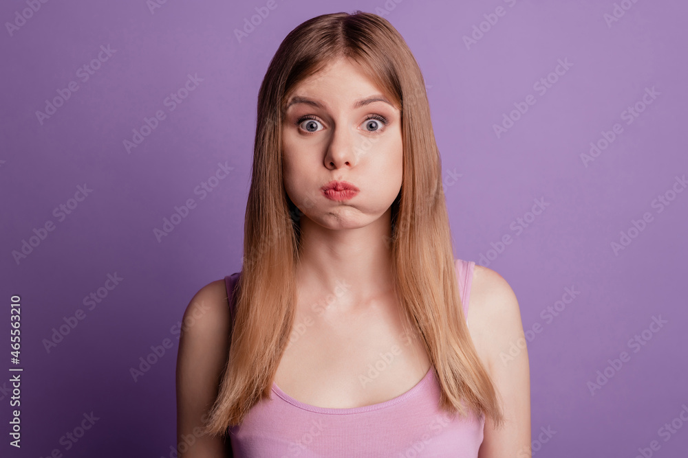 Portrait of nice funny funky lady inflate cheeks look camera fooling around wear pink top on violet background Portrait of nice funny funky lady inflate cheeks look camera fooling around wear pink top on violet background