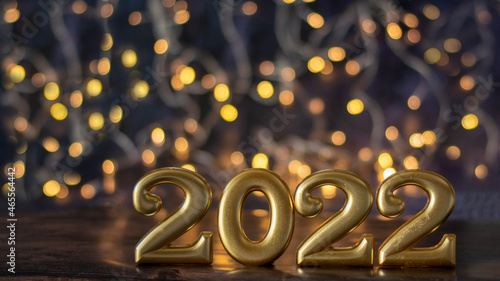 Happy New Year's Day 2022. Golden numbers stand on a fashionable blue background with bokeh lights in the background.