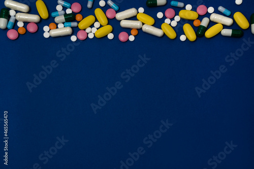 Excessive intake of drugs or vitamins. Blue background with a variety of vitamins or medications