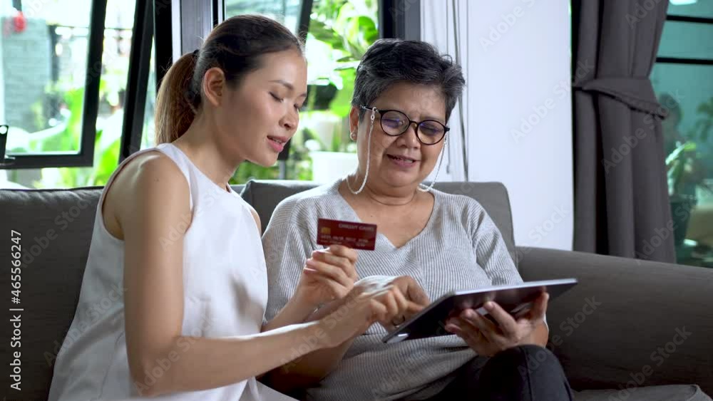 Daughter recommends mother to use credit card for online shopping via tablet, wireless technology, elderly people using technology. Daughter recommends mother to use credit card for online shopping via tablet, wireless technology, elderly people using technology.