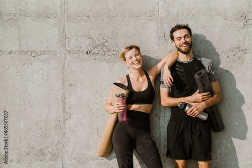 Fototapeta Naklejka Na Ścianę i Meble -  Young man and woman smiling while working out together on parking