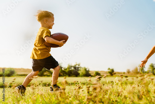 Blonde white boy smiling while playing with rugby ball