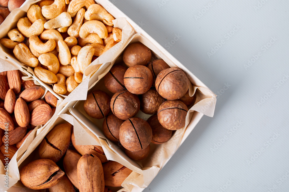 Fototapeta premium Assorted nuts in box nuts: pecan, almond, macadamia, brazil, cashew, hazelnut, Rich in minerals and protein. Healthy nutrition, high in zinc, magnesium and vitamins, online ordering, shoping concept.