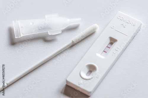 Positive Covid-19 antigen test kit, one step coronavirus antigen rapid test, saliva swab, on a white table, close up 