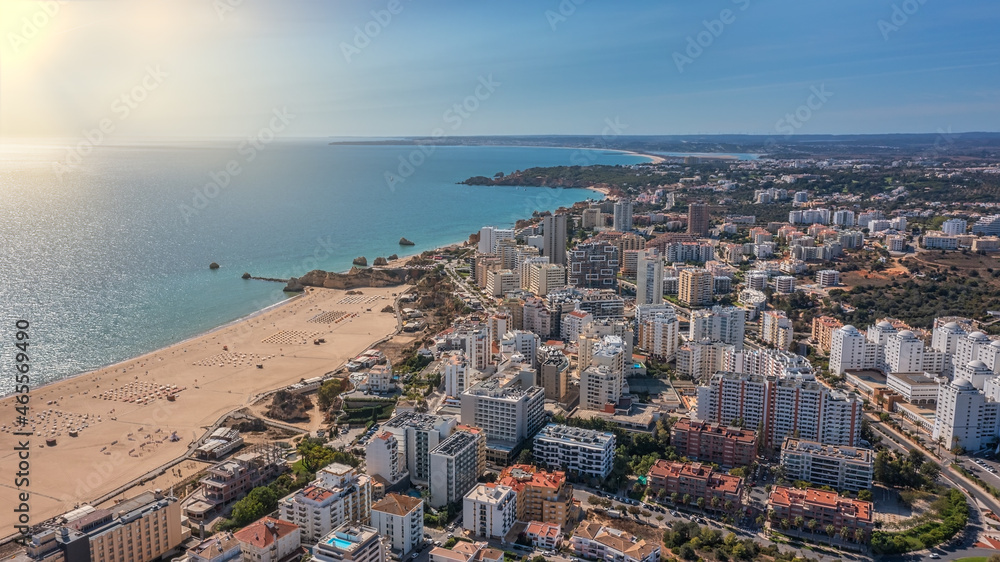 Aerial view of the city of Portimao over residential buildings, high-rise buildings, on the beach Praia de Rocha with tourists. Sunny day
