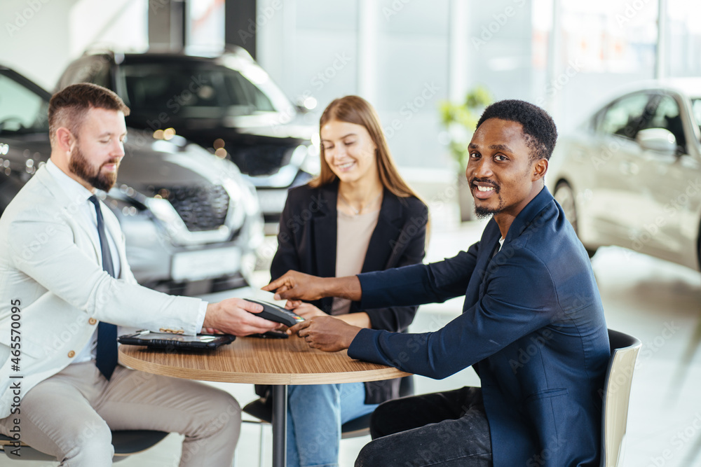 Multiracial couple using credit card for buying new car Multiracial couple using credit card for buying new car