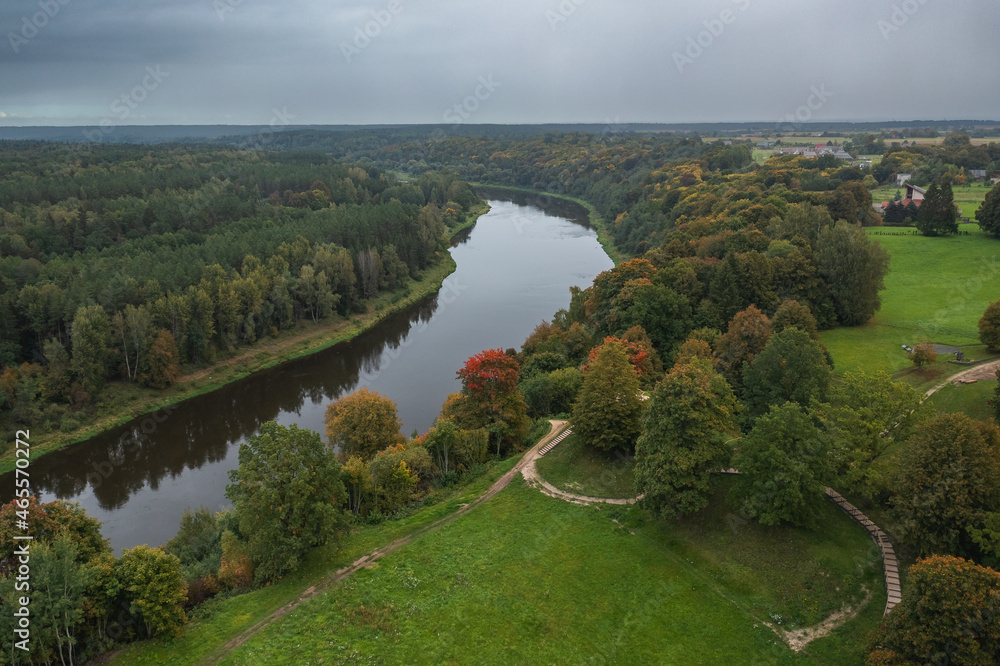 Punia mound in Lithuania with green grass and autumn trees background, road to mountain