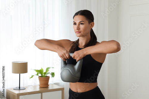 Young woman exercising with kettlebell at home © New Africa