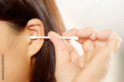 close up female cleaning ear using cotton stick for Healthcare.