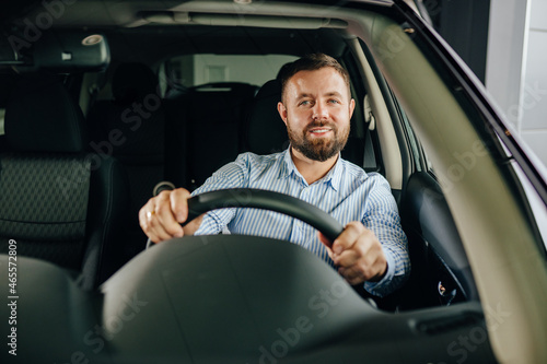 Positive man examining vehicle at salon before purchase