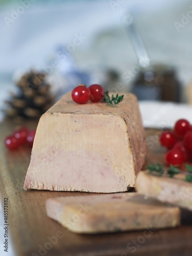 Close up of traditional of fresh French foie gras on a wooden plate with red currant and festive holidays decoration.It is a popular and well-known delicacy in French cuisine photo