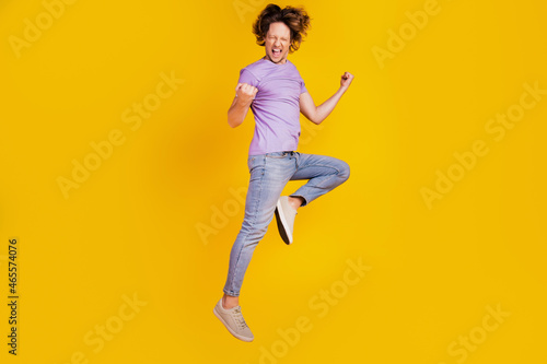 Photo of positive winner champion man jump celebrate victory wear casual jeans clothes on yellow background