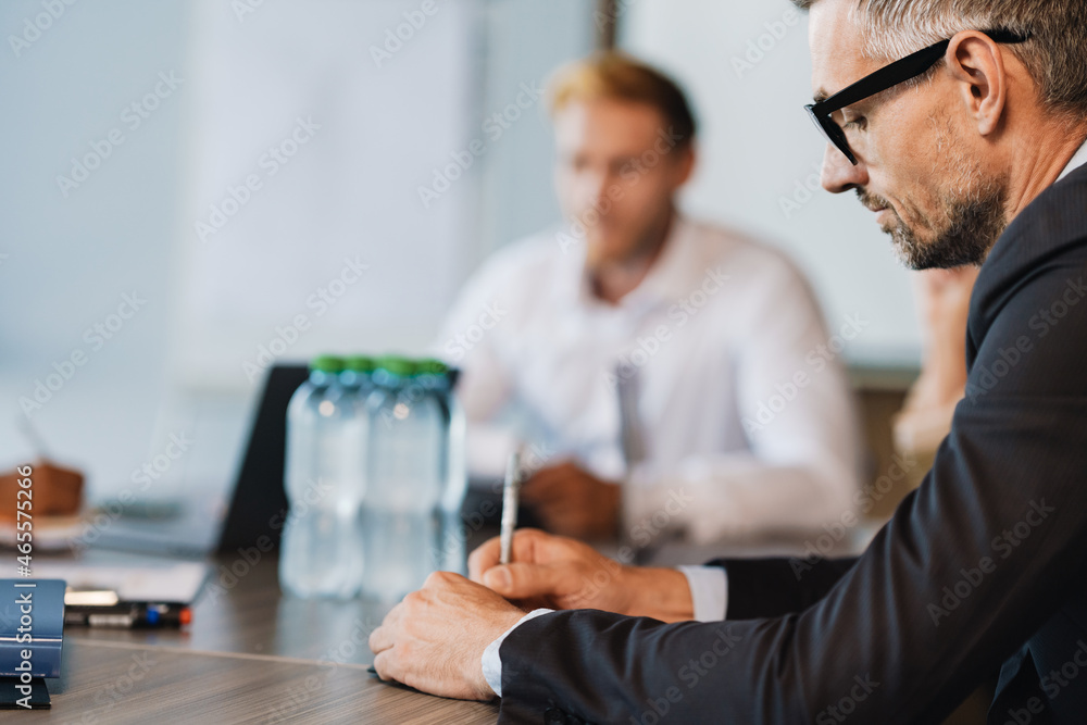 Adult white man in business suit doing paperwork in office Adult white man in business suit doing paperwork in office