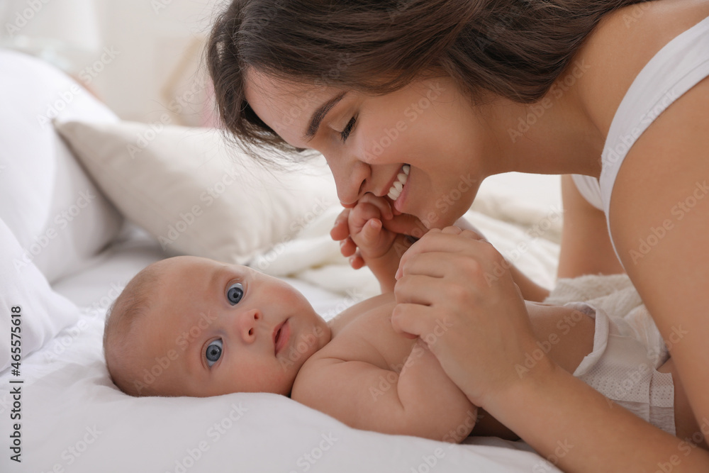 Happy young mother with her cute baby on bed indoors Happy young mother with her cute baby on bed indoors