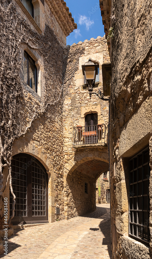 Naklejka premium narrow stone street with an arch in the medieval village of pals on a summer day