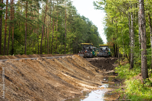 Road construction in the countryside. Road making equipment parked near new uncompleted asphalt road