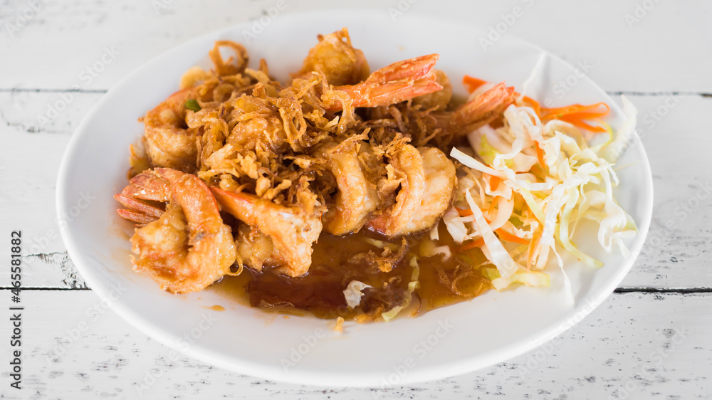 Delicious thai food, deep fried prawns in tamarind sauce on wooden table.