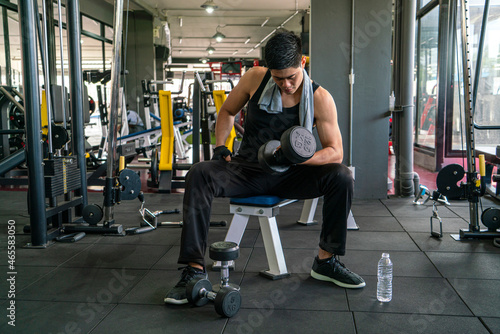 muscular man wearing sportswear using dumbbell bodyweight doing exercise for bodybuilding workout in fitness gym. fitness training, bodyweight building and workout exercise concept