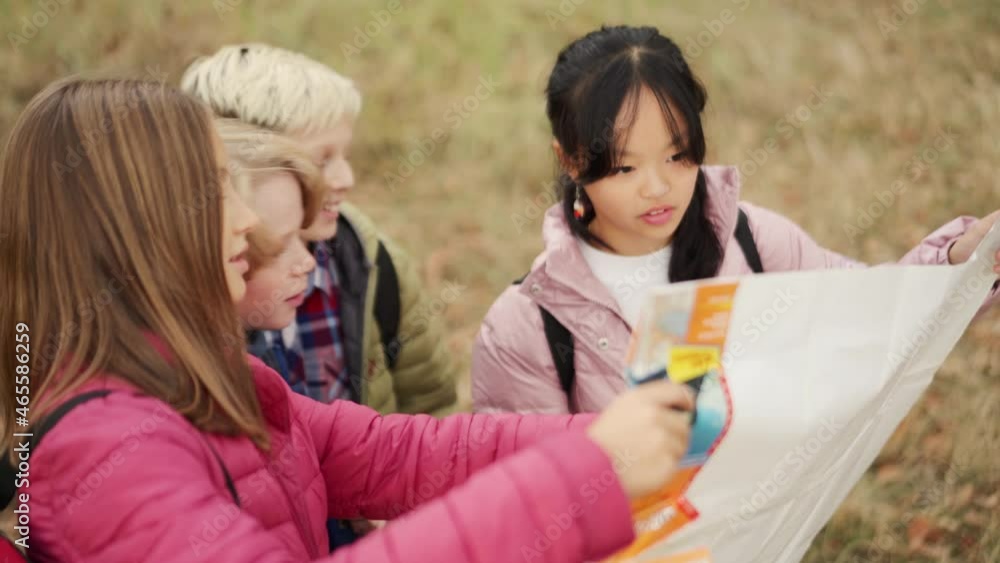 Positive multinational group of children looking at the map in park